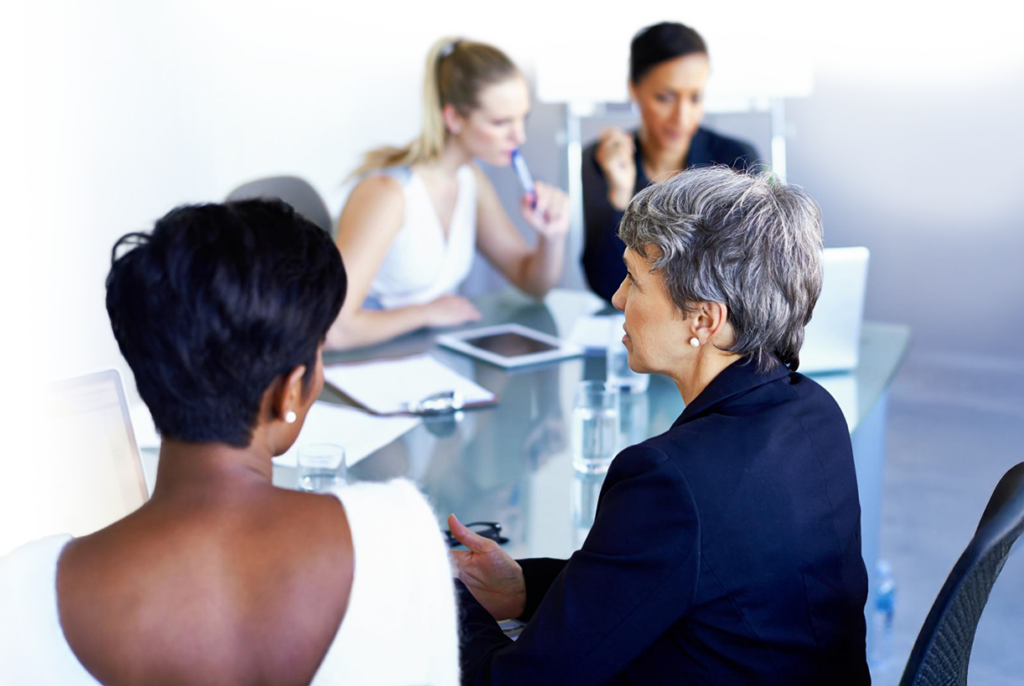 A group of people sitting at a table in a conference room talking.